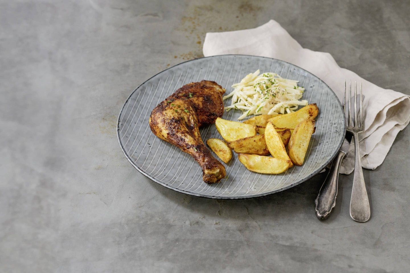 Kartoffelspalten mit Paprika gewürzten Hühnerkeulen.